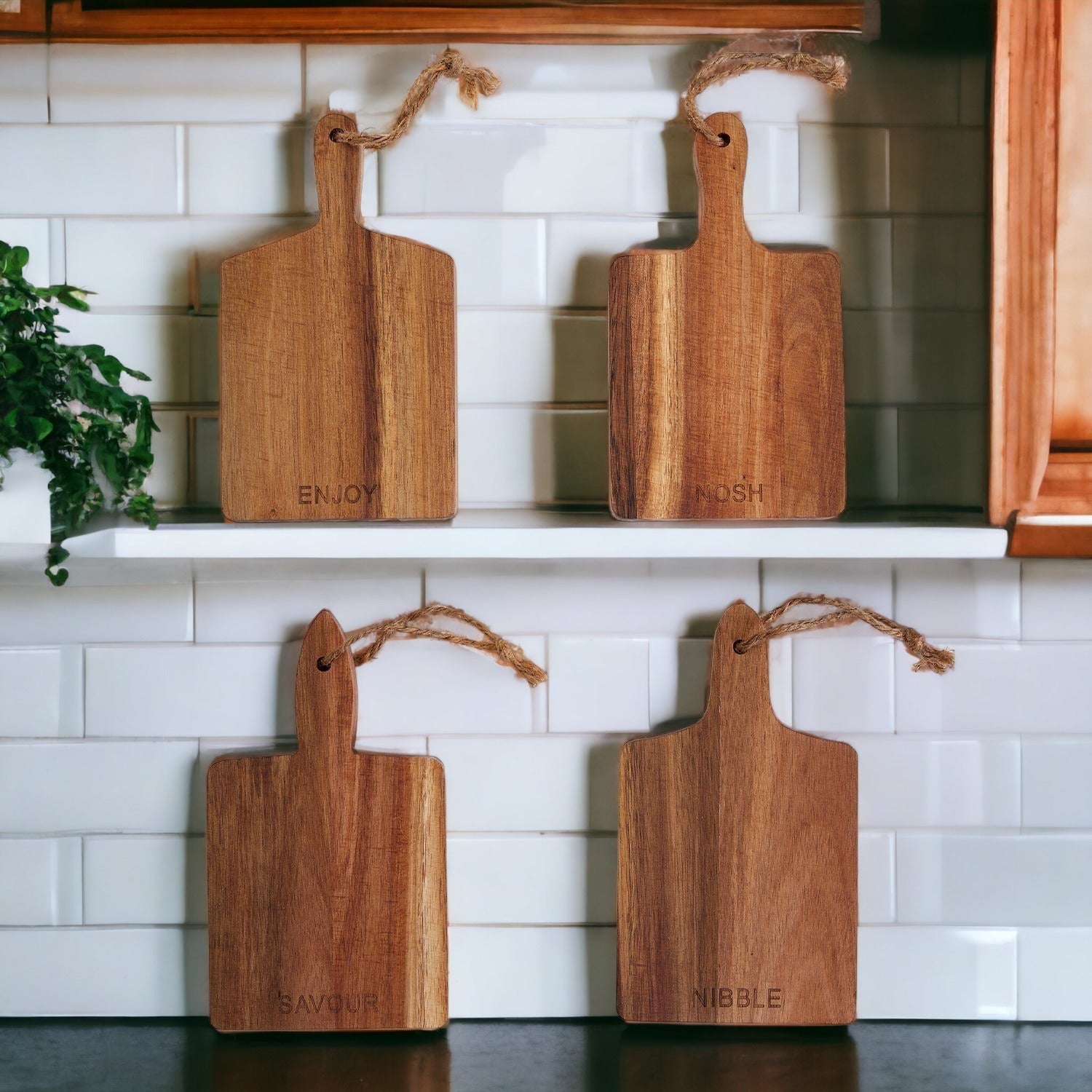 Four wooden cutting boards with engraved words on a kitchen shelf.