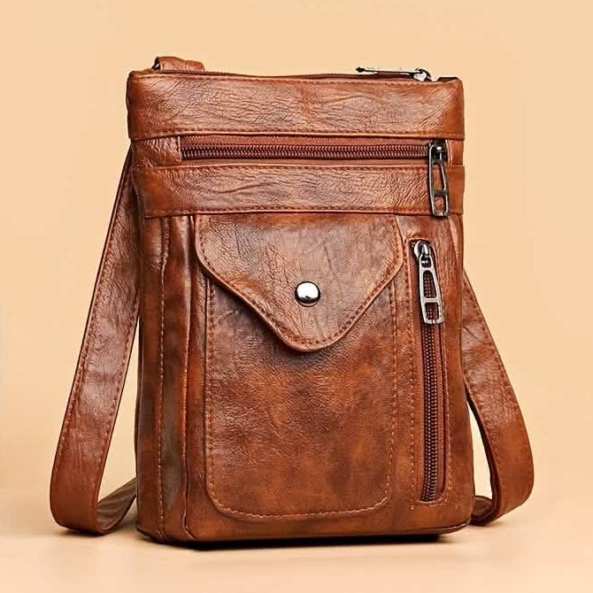 Brown leather crossbody bag on a beige background