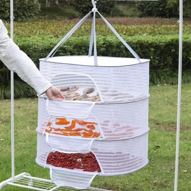 White mesh food dehydrator with various food items being dried outdoors.